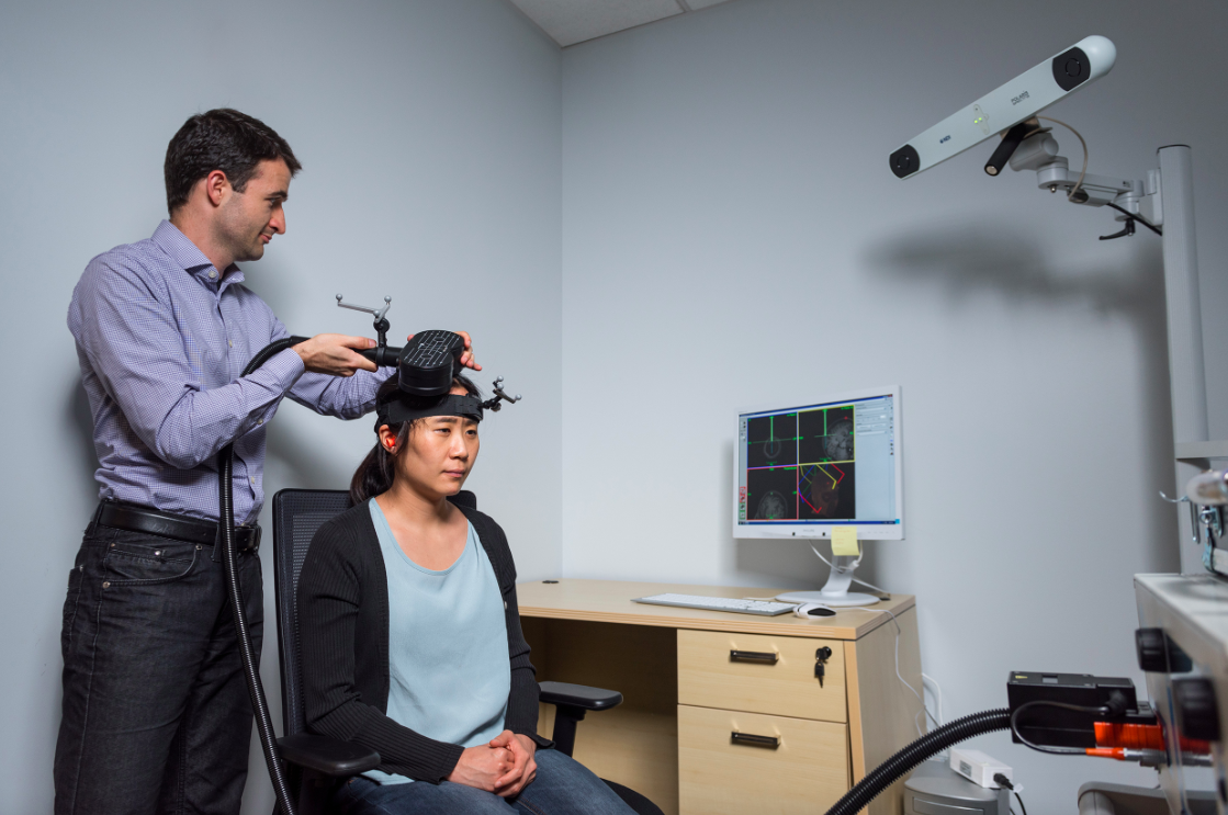 School of Psychology Assistant Professor Dobromir Rahnev demonstrates the application of transcranial magnetic stimulation (TMS) in a Georgia Tech psychology research center with graduate student Ji-Won Jung. (Photo Georgia Tech/Rob Felt)