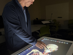 Adam Decker demonstrates how the Anatomage Table turns traditional dissection into a high-tech learning experience. Adam Decker demonstrates how the Anatomage Table turns traditional dissection into a high-tech learning experience.